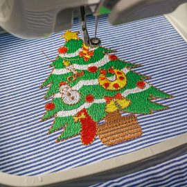 Picture of close up embroidery machines workspace inside hoop finish working embroidery christmas tree design on fabric