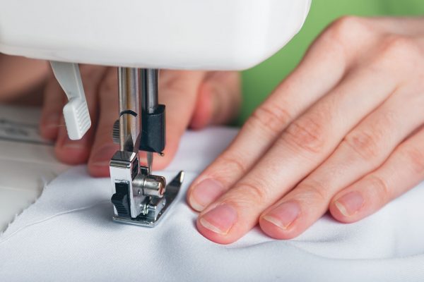 Hands of a young girl on a sewing machine