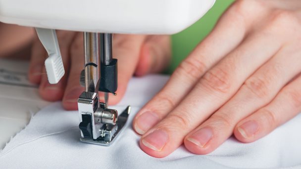 Hands of a young girl on a sewing machine